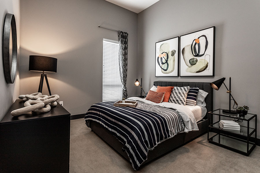 Switching to LED light bulbs will help create an eco-friendly apartment. Contemporary bedroom with grey paint, lamps, and wall art.