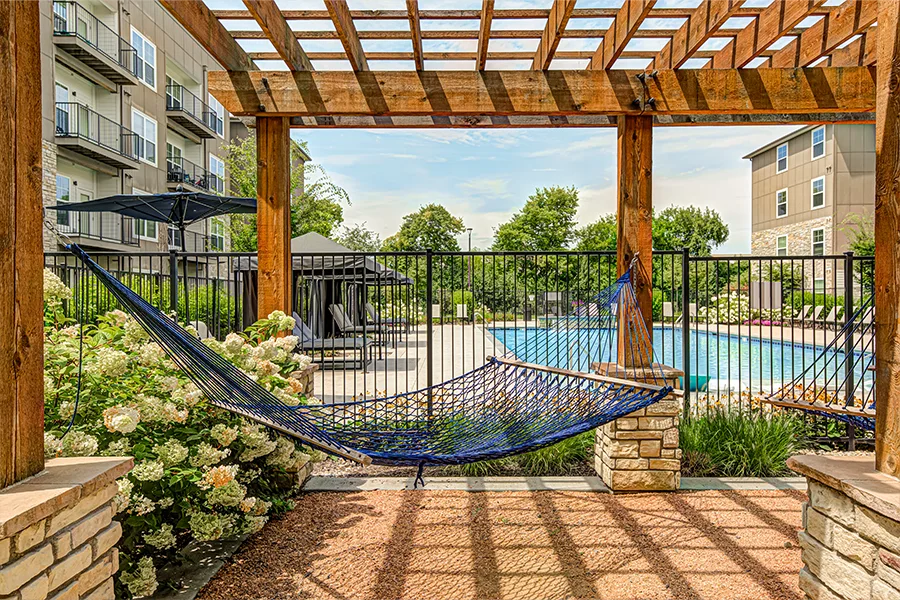 A hammock overlooking the blue pool at The Verge Apartments